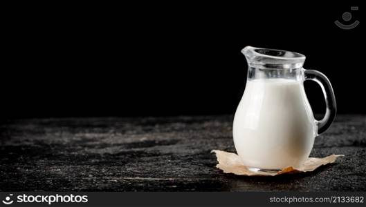 A full jug of fresh milk. On a black background. High quality photo. A full jug of fresh milk.