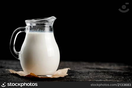 A full jug of fresh milk. On a black background. High quality photo. A full jug of fresh milk.