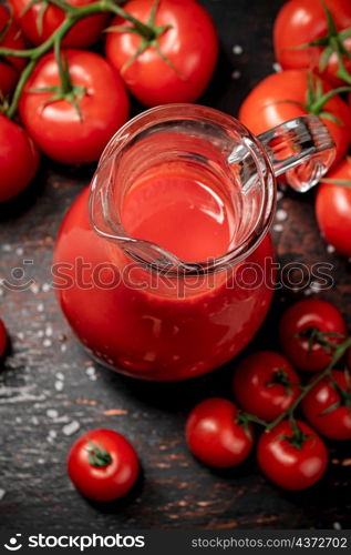 A full jug of tomato juice. On a rustic dark background. High quality photo. A full jug of tomato juice.