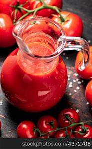 A full jug of tomato juice. On a rustic dark background. High quality photo. A full jug of tomato juice.