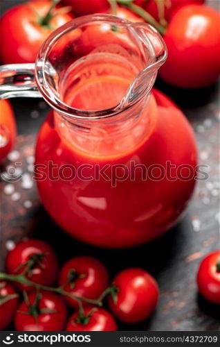 A full jug of tomato juice. On a rustic dark background. High quality photo. A full jug of tomato juice.