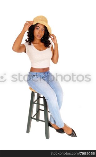 A full length image of a African American women in a beige blouseand a straw hat sitting on a chair, isolated for white background.