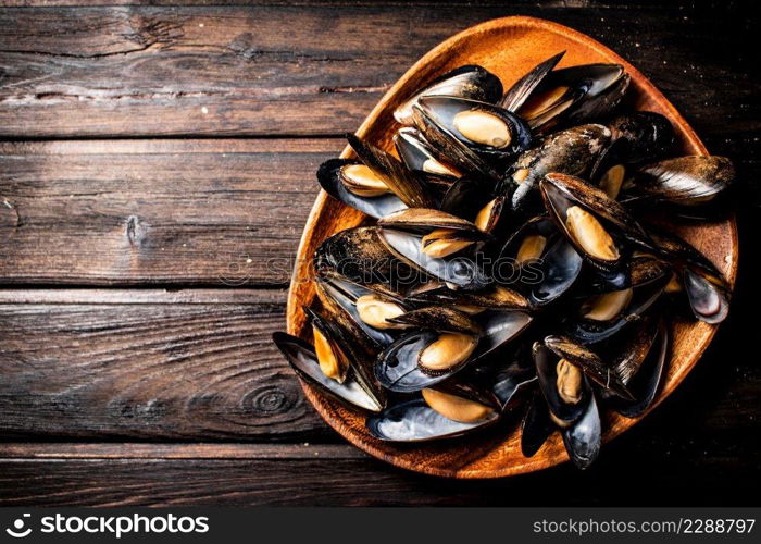 A full plate of delicious mussels. On a wooden background. High quality photo. A full plate of delicious mussels. 