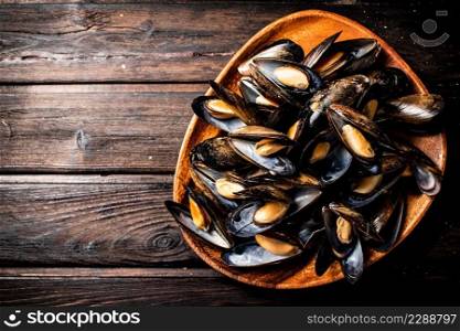 A full plate of delicious mussels. On a wooden background. High quality photo. A full plate of delicious mussels. 