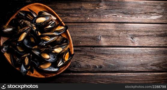 A full plate of delicious mussels. On a wooden background. High quality photo. A full plate of delicious mussels.