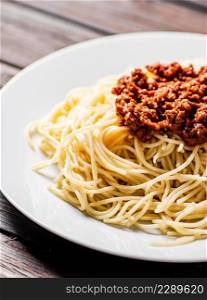 A full plate of spaghetti bolognese on the table. On a wooden background. High quality photo. A full plate of spaghetti bolognese on the table.