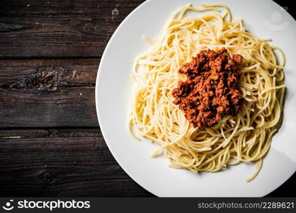 A full plate of spaghetti bolognese on the table. On a wooden background. High quality photo. A full plate of spaghetti bolognese on the table.