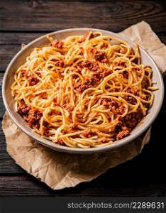 A full plate of spaghetti bolognese on the table. On a wooden background. High quality photo. A full plate of spaghetti bolognese on the table.