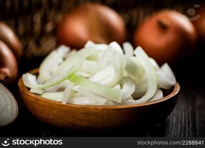 A full wooden plate with pieces of onion. On a wooden background. High quality photo. A full wooden plate with pieces of onion.