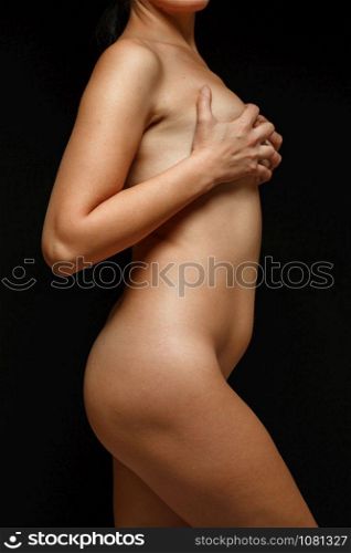 a fully Nude woman covering her body with postpartum and age related changes on a black background