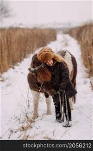 A fun winter story of a girl and a pony.. A two-colored pony and a child walk through a snow field 3092.