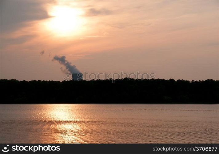 A functioning nuclear power plant on a lake at sunset.. Nuclear Sunset