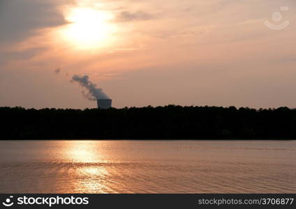 A functioning nuclear power plant on a lake at sunset.. Nuclear Sunset