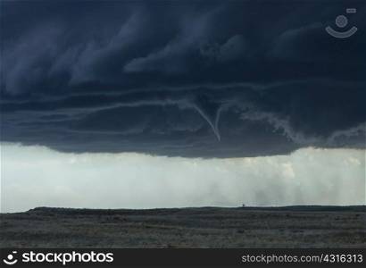 A funnel cloud looms ominously over the open prairie