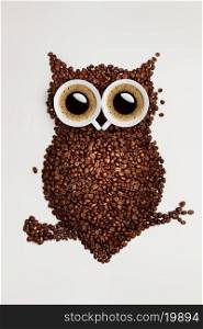 A funny owl made of roasted coffee beans and two cups.
