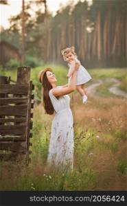 A gentle portrait of a mother and daughter in nature.. A young beautiful mother holds her daughter in her arms 2997.