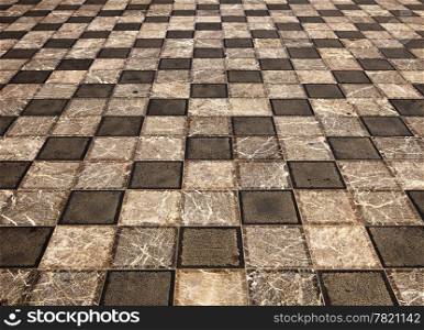 A geometric pattern of gray marble square tiles is laid out in a piazza or public square in Taormina on Sicily in Italy.