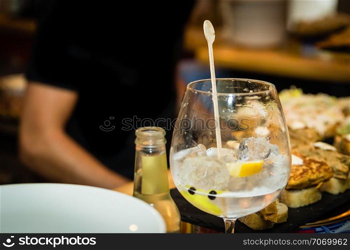 A gin and tonic glass on a bar table