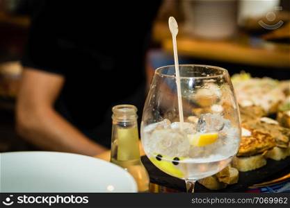 A gin and tonic glass on a bar table