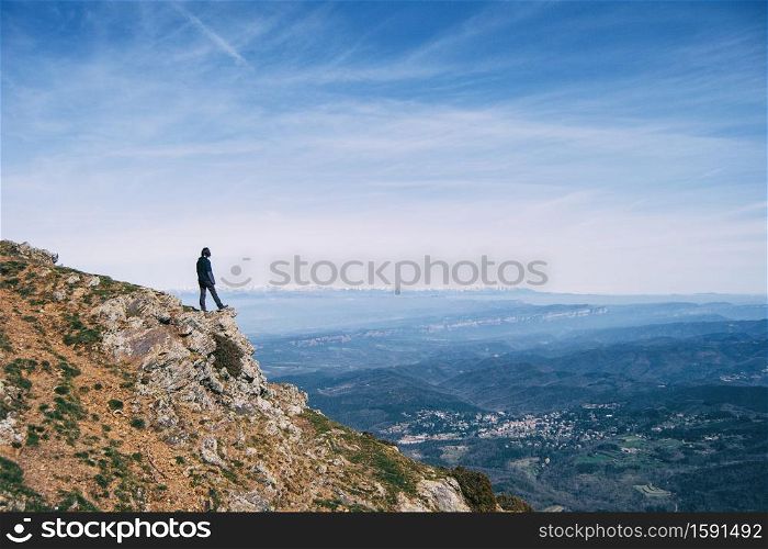 A girl contemplating the landscape from the top of a rock
