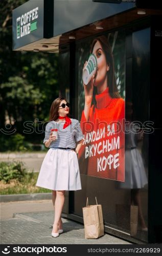 A girl drinks coffee on the background of a poster with a girl with coffee.. Photo imitation of coffee sales 4213.