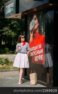 A girl drinks coffee on the background of a poster with a girl with coffee.. Photo imitation of coffee sales 4213.