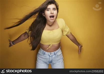 A girl expressing various emotions on her face under the yellow color, expression in the eyes, laughter with white teeth, grimace, joy of life and full of energy on her body.