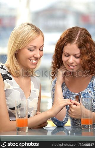 A girl-friend shows a ring a girl-friend in a cafe