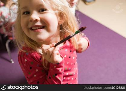 A girl holding a paintbrush