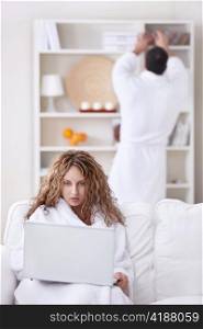 A girl in a bathrobe looking at a laptop in the foreground