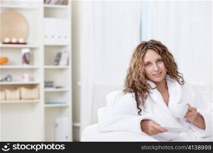 A girl in a bathrobe with a cup of coffee at home