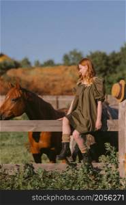 A girl in a green dress is stroking and feeding horses.. A girl with red hair strokes and feeds grass to horses 3251.