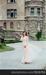 A girl in a light pink dress against the background of a medieval Polish stone castle