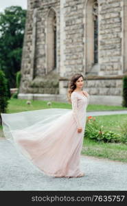 A girl in a light pink dress against the background of a medieval Polish stone castle