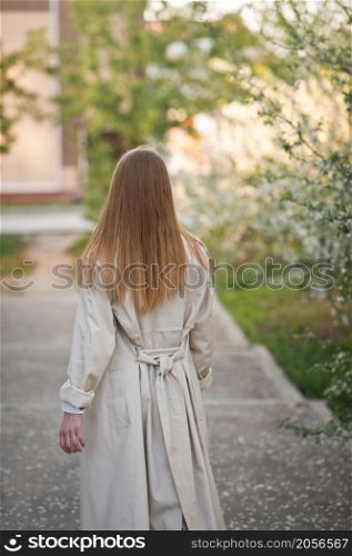 A girl in a raincoat stands with her back to the viewer.. Portrait of a girl from the back going into the distance 2949.