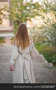 A girl in a raincoat stands with her back to the viewer.. Portrait of a girl from the back going into the distance 2949.