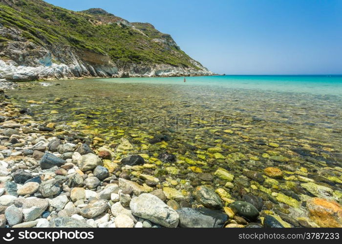 A girl in a red bikini standing in the crystal clear mediterranean at Giottani beach on the west coast of Cap Corse in Corsica