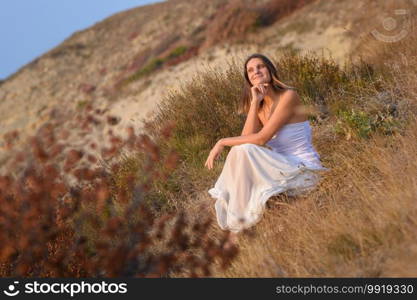 A girl in a white dress enjoys a beautiful view of the sunset