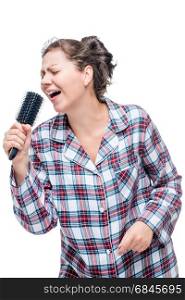 A girl in pajamas loves a song to sing, instead of a microphone . A girl in pajamas loves a song to sing, instead of a microphone a hairbrush on a white background