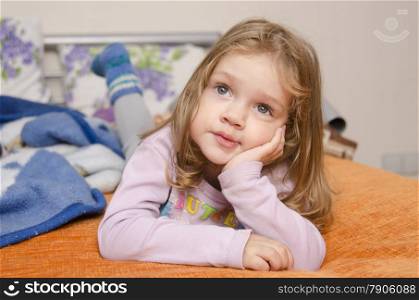 A girl laying on the couch and enthusiastically watching TV