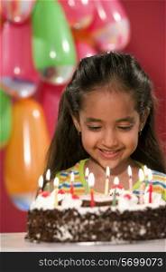 A girl looking at her birthday cake