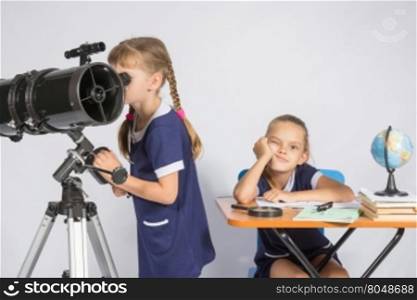 A girl looks through a telescope, the other girl is waiting sad results