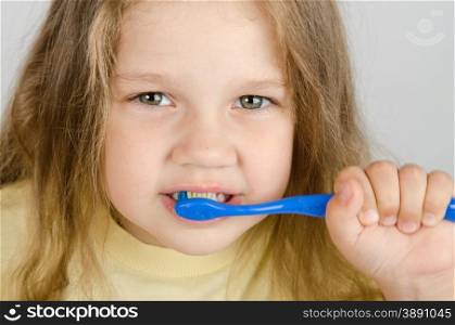 A girl of four years old brushing his teeth with a toothbrush. Close-up of a girl cleaning teeth