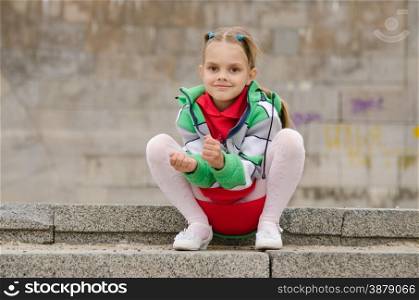 A girl of six years walking on the embankment. Six-year girl sits on the granite steps