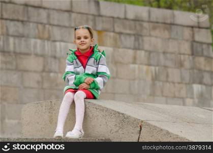 A girl of six years walking on the embankment. Girl sitting a granite embankment on ramp