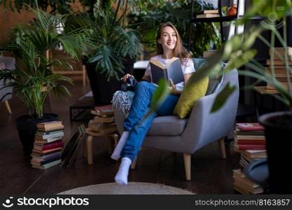 a girl photographer with a camera smiles while sitting in a chair with many books
