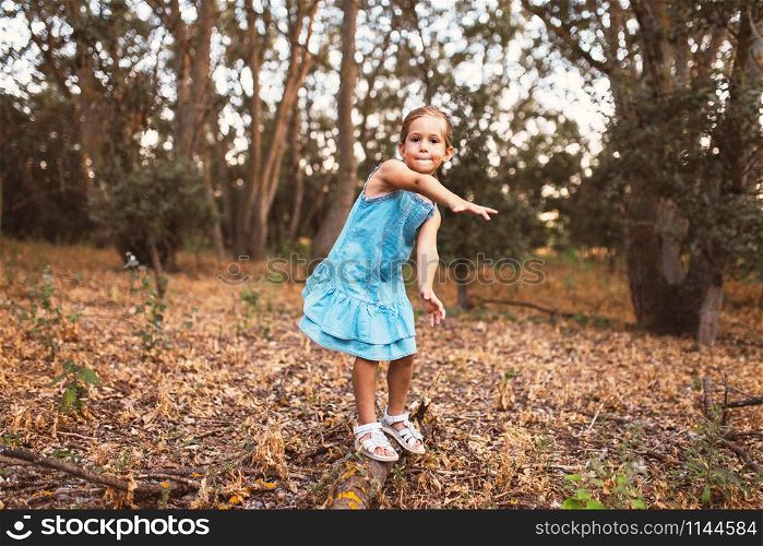 A girl plays swinging over a trunk in the forest