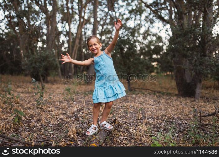 A girl plays swinging over a trunk in the forest
