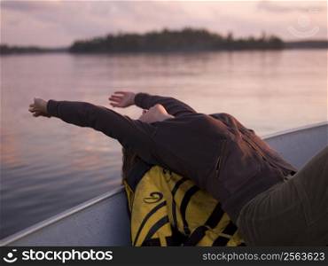 A girl relaxing on the boat at sunset, Lake of Woods, Canada