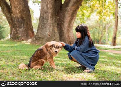 A girl sits with a brown dog in the garden.
